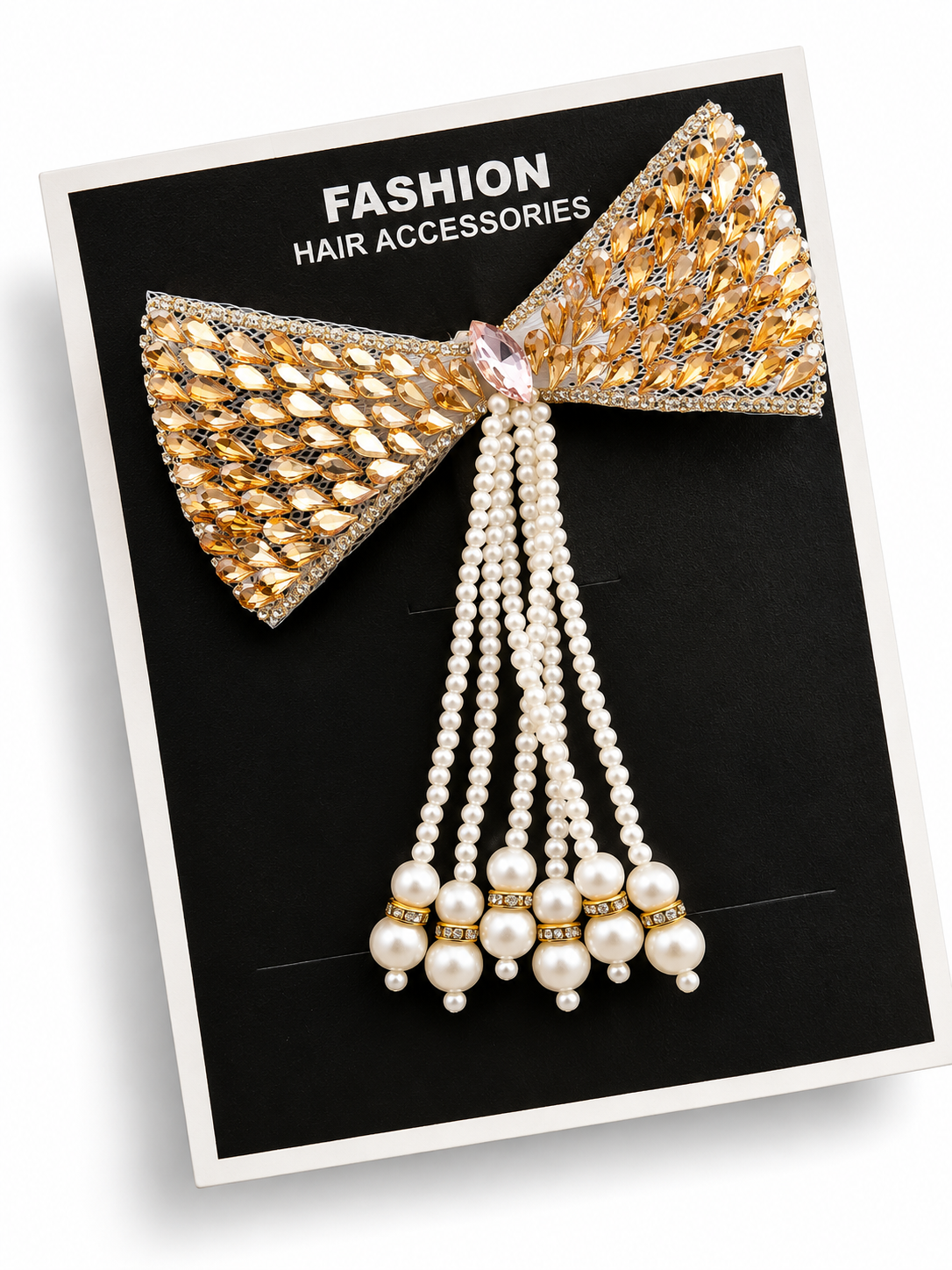 Gold crystal bow hair clip with long pearl tassels shown on a black display card