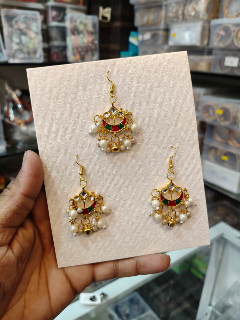 Matching gold-tone red and green ornaments with pearl drops displayed on an ivory card